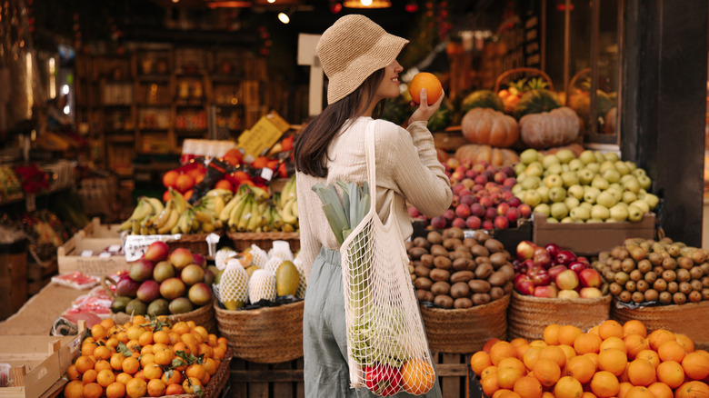 woman smelling orange in a produce shop