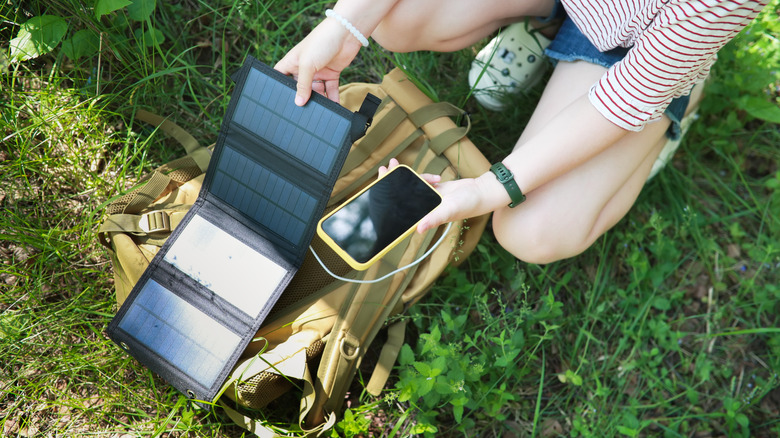 A person charging a phone with foldable portable solar panels.