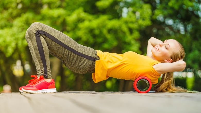A woman using a foam roller outdoors