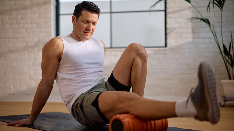 A man using a foam roller on his leg