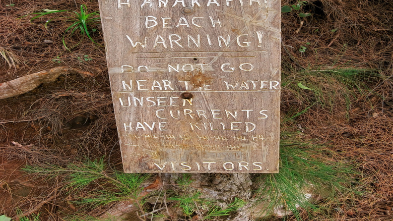a wooden sign warning to stay out of the water