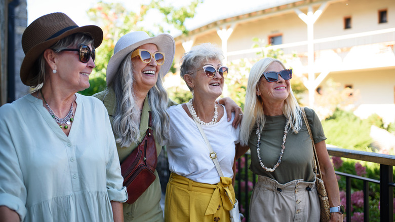Four senior women smile and pose together in a sunny location