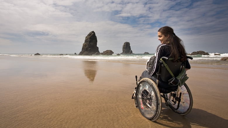 A woman in a wheelchair smiles on a beach