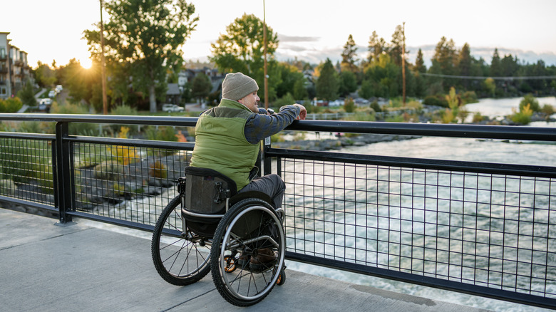 A man in a wheelchair on a bridge over a river