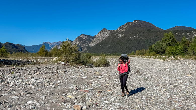 A woman hiking in a dry riverbed.