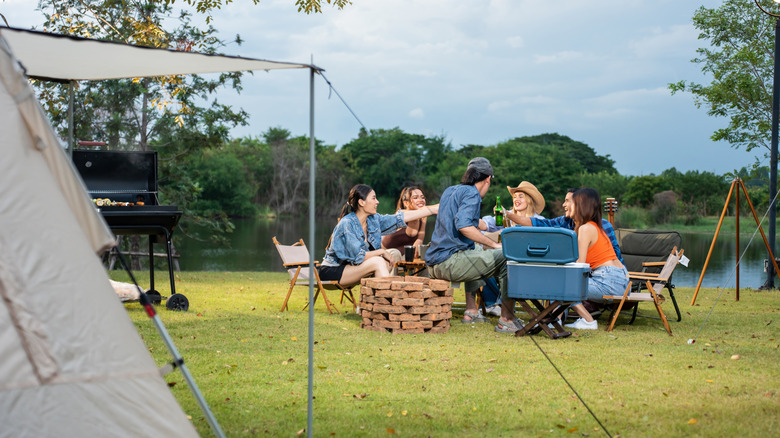 diverse group of friends having outdoors camping party by a lake