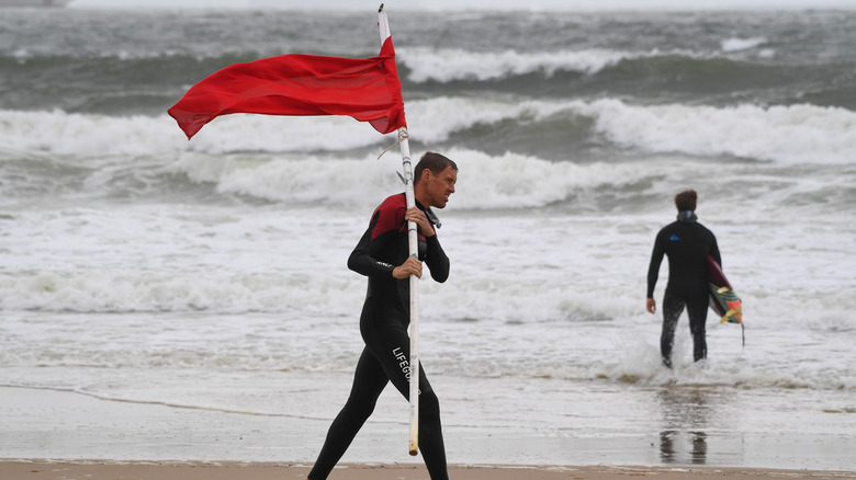 A lifeguard carrying a red flag 