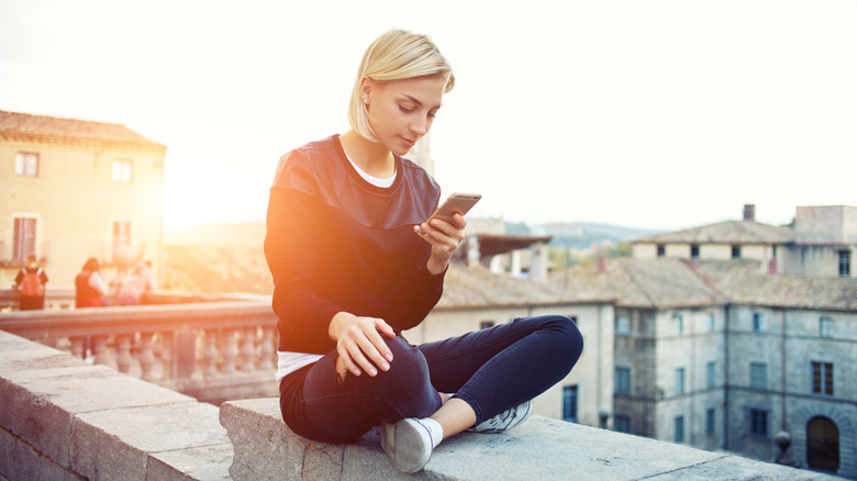 Woman using smartphone on building