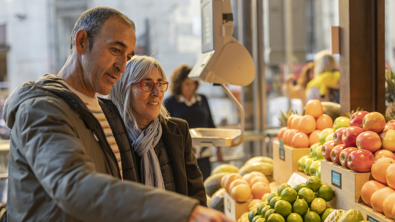 man and women choosing produce at market