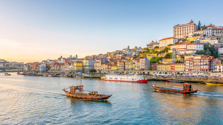 View of the city of Porto in Portugal in warm winter sunset light with boats and Douro river in foreground