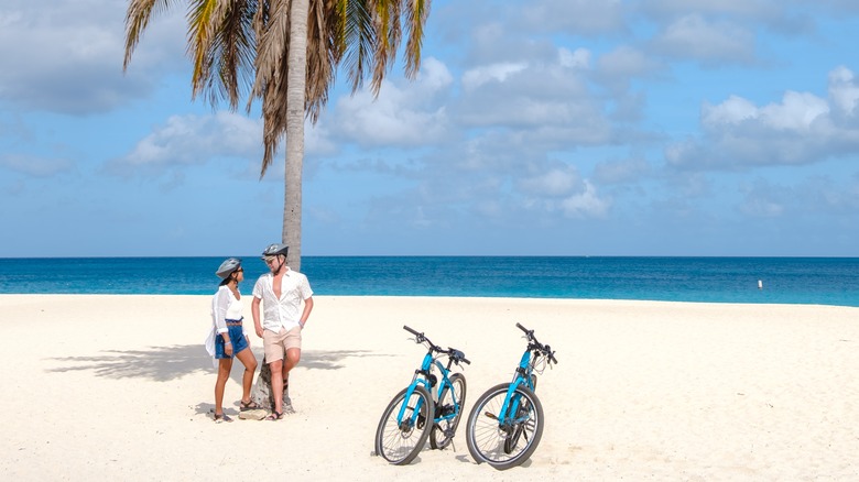 man and woman with bikes on the beach