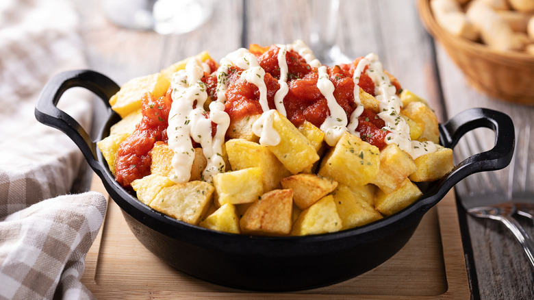 A pan full of patatas bravas on a table