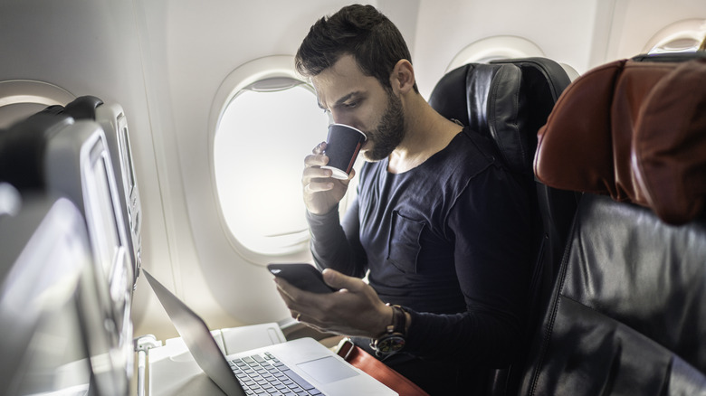 Man drinking coffee on plane 