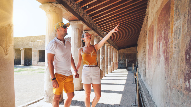 Couple holding hands pointing at wall painting