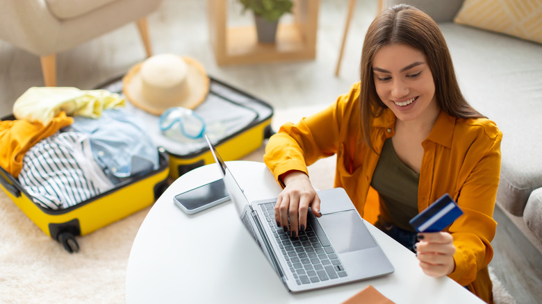 A woman using her credit card to book travel on her laptop