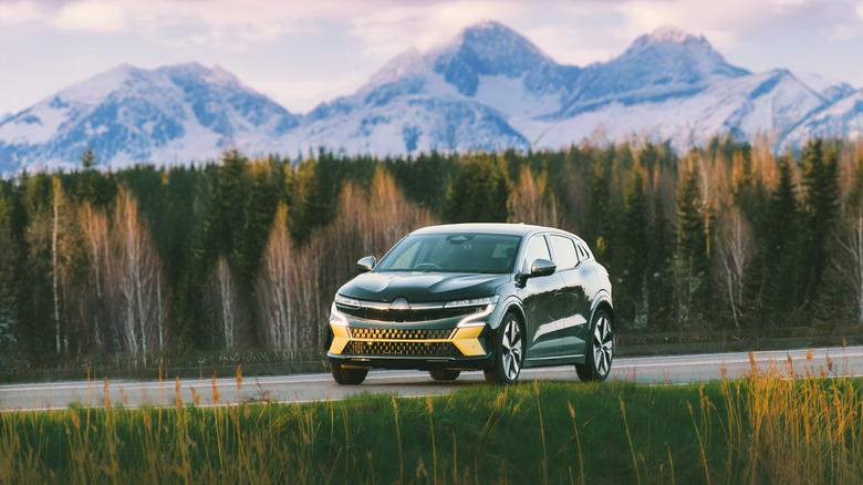 Modern electric car cruising country highway with mountain background