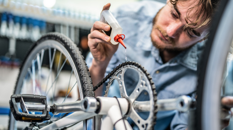 man putting lubricant on chain