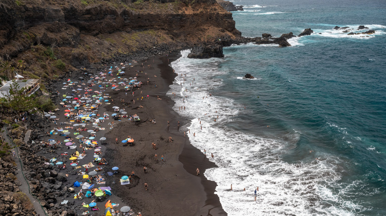a crowded beach on the black sands in Tenerife in the Canary Islands
