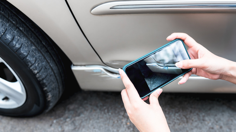 person taking photo of car damage