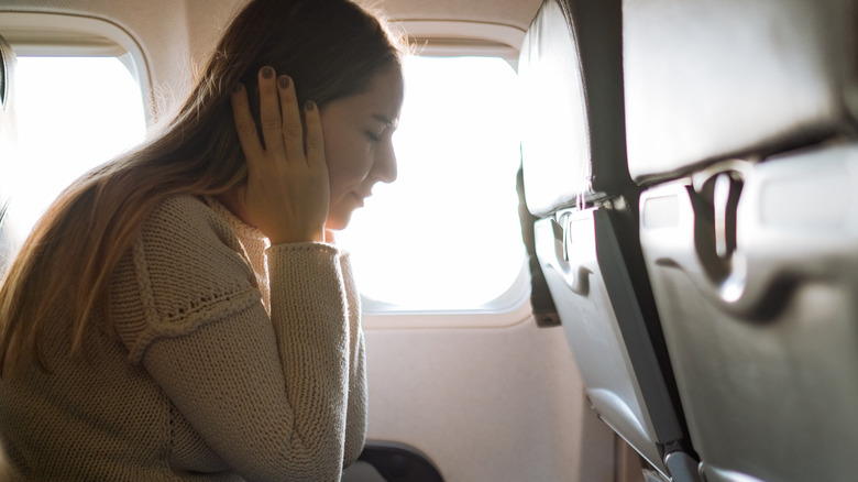 Woman experiencing ear pain in-flight