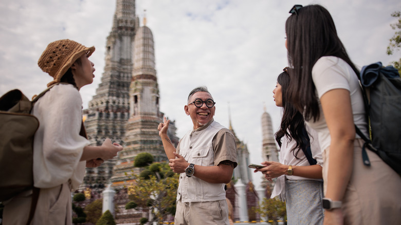man showing a historic Asian building to tourists