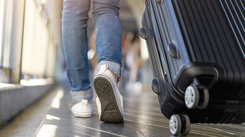 Traveler with suitcase wearing sneakers