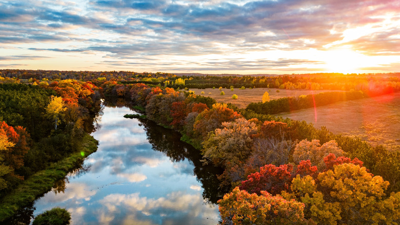 A calm tree-lined river in autumn with Wisconsin fields in the background