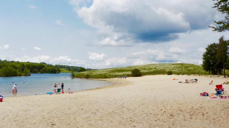 people stand and lay on the wide sandy beach of Wazee Lake