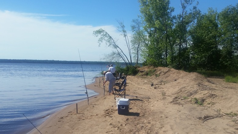 anglers on sandy Petenwell Lake beach with fishing poles and supplies
