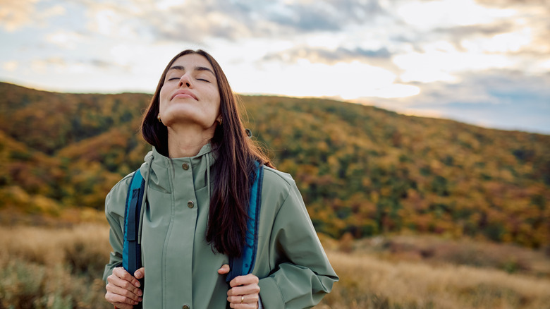 A woman on a hike breathes in the fresh air.