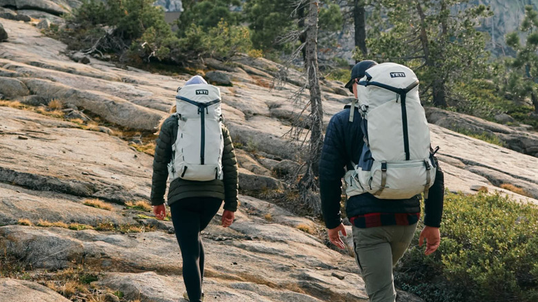 Two people hiking wearing Yeti backpacks.