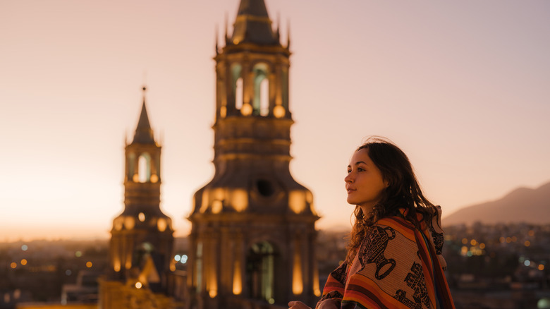 woman in a poncho overlooking a basilica in Arequipa, Peru