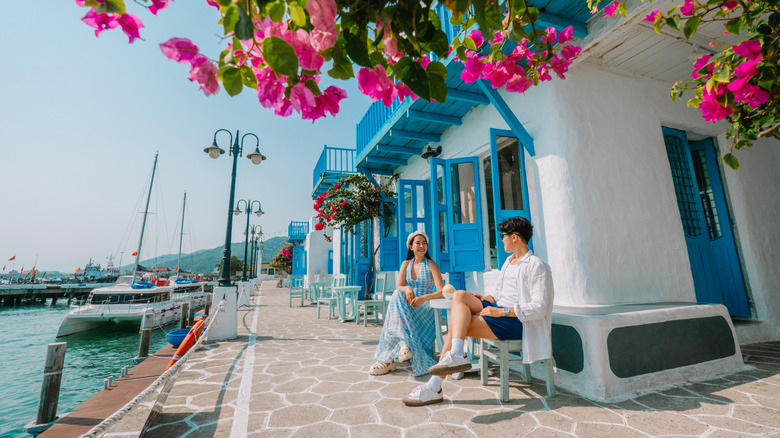 a man and woman sitting outside of a white building at a marina in Da Nang, Vietnam