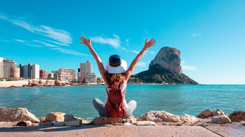 woman sitting with her hands in the air in front of the water