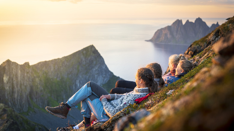 four friends sitting on a cliff's edge overlooking a beautiful bay view in Norway