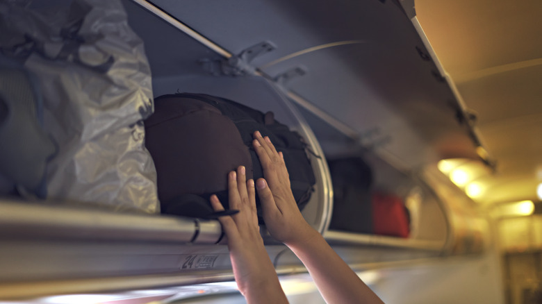 putting luggage in overhead bin