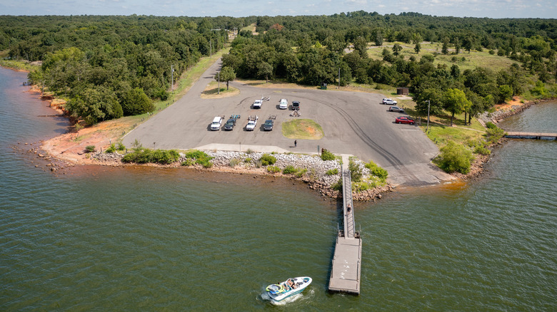 Boat and dock on the water by a large parking lot and trees at Lake Thunderbird State Park in Oklahoma