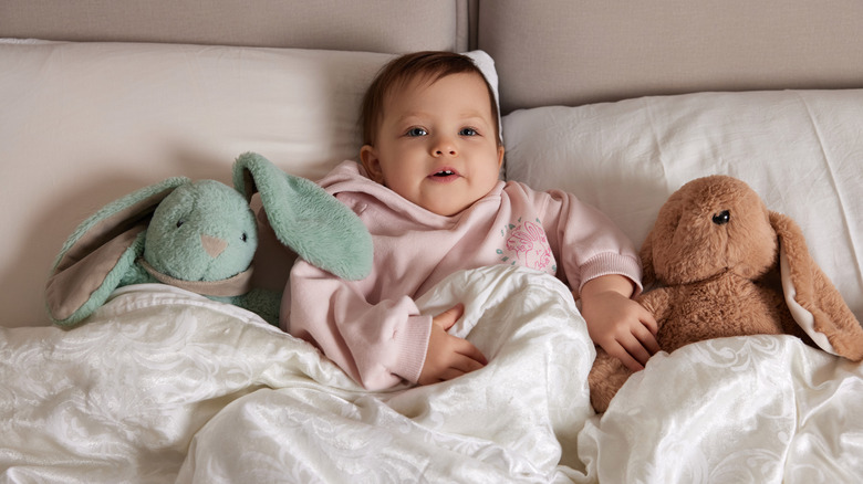 Baby in bed with stuffed animals